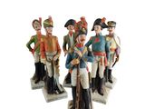 trois figurines représentant des hommes vêtus d'uniformes militaires et portant des casquettes