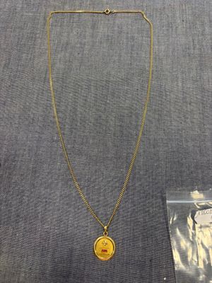un collier en or orné d'une pièce, à côté d'un sac en plastique