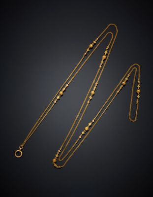 un collier en or et une chaîne en or ornée de perles sur fond noir