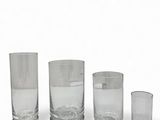 three clear glass vases and one empty glass on a white surface