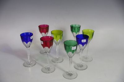 several different colored wine glasses are lined up on a white surface
