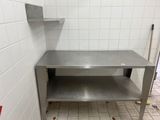 une table en acier inoxydable avec une étagère au milieu de la pièce
