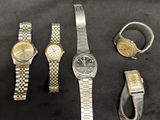 three watches and a ring are sitting on a black surface