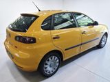 the back of a yellow car is parked in a white room
