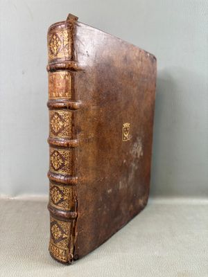 un vieux livre relié en cuir aux tranches dorées posé sur une table