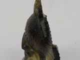 figurine of a bird perched on a rock on a white surface