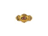 gros plan d'une bague en or avec une pierre rouge au centre