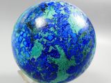 a close up of a blue and green marble ball on a clear base