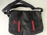sac messager en cuir noir avec des sangles rouges et un motif représentant une tête de mort et des os croisés