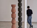 un homme debout dans une pièce, avec trois grands vases devant lui