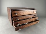 an image of a wooden drawer with four drawers and a pen in it