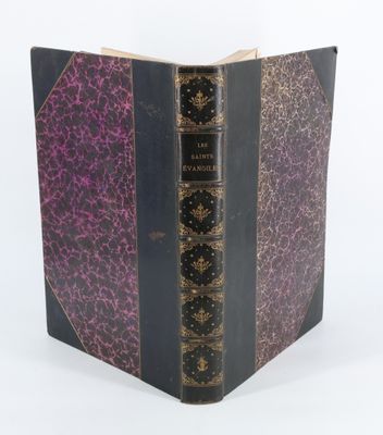 un vieux livre à la couverture violette posé sur une table blanche