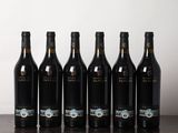 des bouteilles de vin alignées sur une table devant un mur blanc