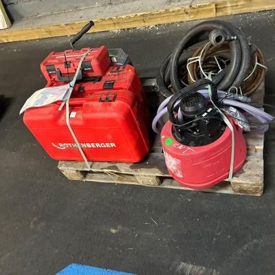 two red gas canisters on a pallet with a hose attached to them