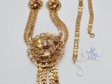 a close up of a gold necklace with a red stone on it