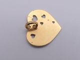 a close up of a gold heart shaped pendant on a gray surface