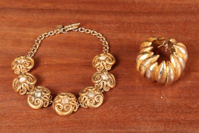 un bracelet en or et une citrouille en or posés sur une table en bois