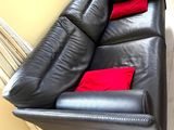 a black leather couch with red pillows in a living room