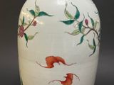 a white vase with red flowers and green leaves on it