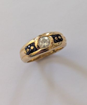 un gros plan d'une bague en or sertie d'un diamant blanc et de diamants noirs