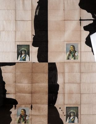 un homme debout devant un mur sur lequel sont accrochées des photos de personnes