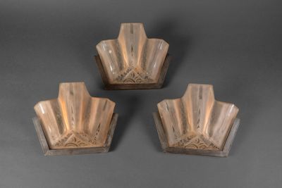 trois appliques en verre posées sur une surface grise, sur fond gris