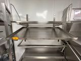 des étagères en acier inoxydable dans une cuisine professionnelle disposant d'un grand plan de travail