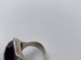 a close up of a silver ring with a purple stone on it