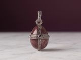 sterling silver pendant with a red stone and diamonds on a marble surface