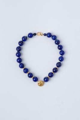 un bracelet en perles bleues orné d'une breloque en forme de pièce d'or