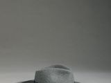 un chapeau gris posé sur une table blanche