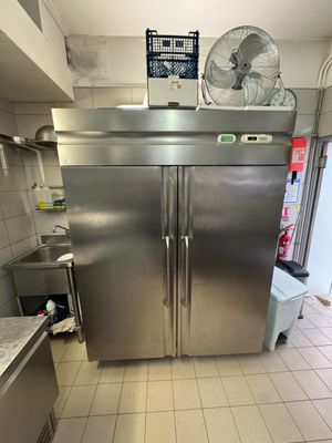 a large stainless steel refrigerator in a kitchen with a fan on top of it