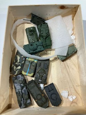 des véhicules militaires miniatures dans une boîte en bois posée sur une surface blanche