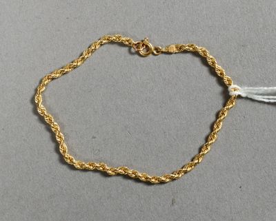 gros plan d'un bracelet en chaîne en or sur une surface grise