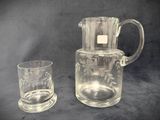 a glass pitcher and a glass cup next to each other