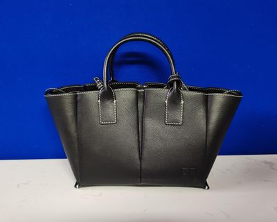 un sac à main en cuir noir posé sur une table blanche
