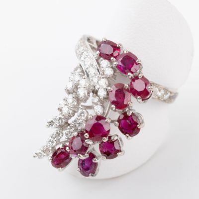 une photo en gros plan d'une bague sertie d'un diamant et d'un rubis sur une surface blanche