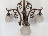 a chandelier with three glass shades hanging from the ceiling