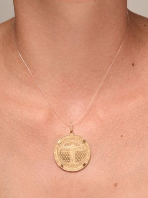 a close up of a person wearing a necklace with a coin on it