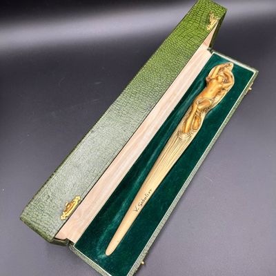 un stylo en bois dans une boîte verte, muni d'un manche en bois