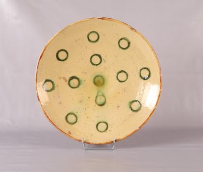 une assiette jaune ornée de cercles verts, posée sur un support