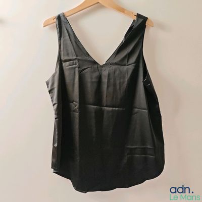 a black top hanging on a wall with a wooden hanger