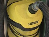 a yellow vacuum sitting on the floor next to a green hose