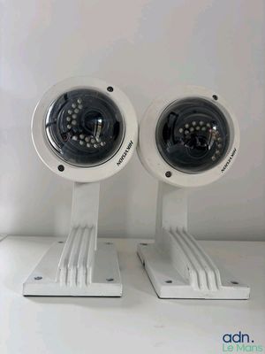 pair of white surveillance cameras mounted to a white wall