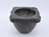 a small black bowl with a handle on a white surface