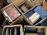 Plusieurs cartons remplis de livres sont empilés sur une table dans un salon.