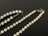a close up of a necklace with pearls on a black surface