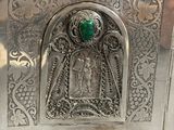 a silver box with a green stone in it