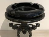 a black ashtray on a stand on a wooden table