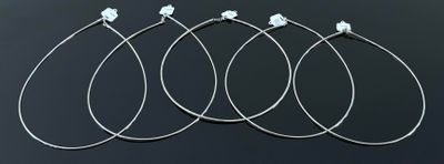 quatre paires de boucles d'oreilles créoles en argent posées sur une surface noire